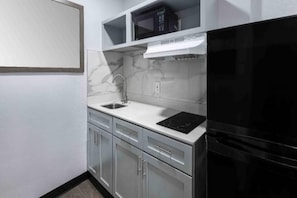 A kitchen with a black refrigerator, a microwave, a sink, and a stove. - 1 Queen Bed | Smoking, Kitchen (Hickory)
