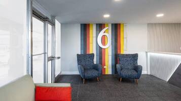 A modern waiting area with two armchairs, a red cushion, and a large number '6' on the wall.