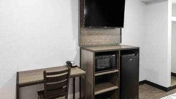 Una habitación compacta con escritorio, silla y un refrigerador pequeño.