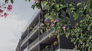 A multi-story building with balconies, a sign reading 'CITY PARK LIVING,' and a clear sky.