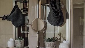 Een badkamer met spiegel, wastafel, handdoekrek en potplanten.