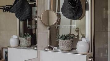 A bathroom with a mirror, sink, towel rack, and potted plants.
