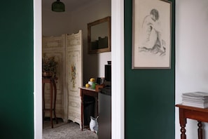 Una habitación con un escritorio, una silla, un espejo y una obra de arte enmarcada en la pared.