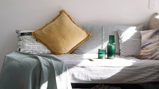 Een kamer met een bed, een ronde spiegel, twee ingelijste foto's en een groene hanglamp.