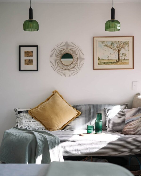 A room with a bed, a round mirror, two framed pictures, and a green pendant light. - Mac & Sylvia Luxe Spa Bath City Escape (Launceston)