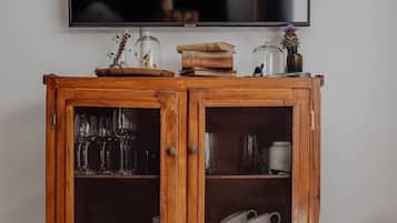 Een houten kast met glazen deuren, gevuld met keukengerei en boeken.