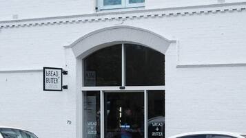 Um edifício branco com uma placa que diz 'BREAD + BUTTER' e um veículo estacionado na frente.
