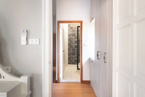 A hallway with a wooden floor, a white door with brass handles, and a patterned wall. - Naka Pool Villa Pratumnak Pattaya (Pattaya City)