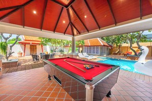 Een buitenzwembad met een pooltafel, lounge stoelen en een decoratieve zwaan.