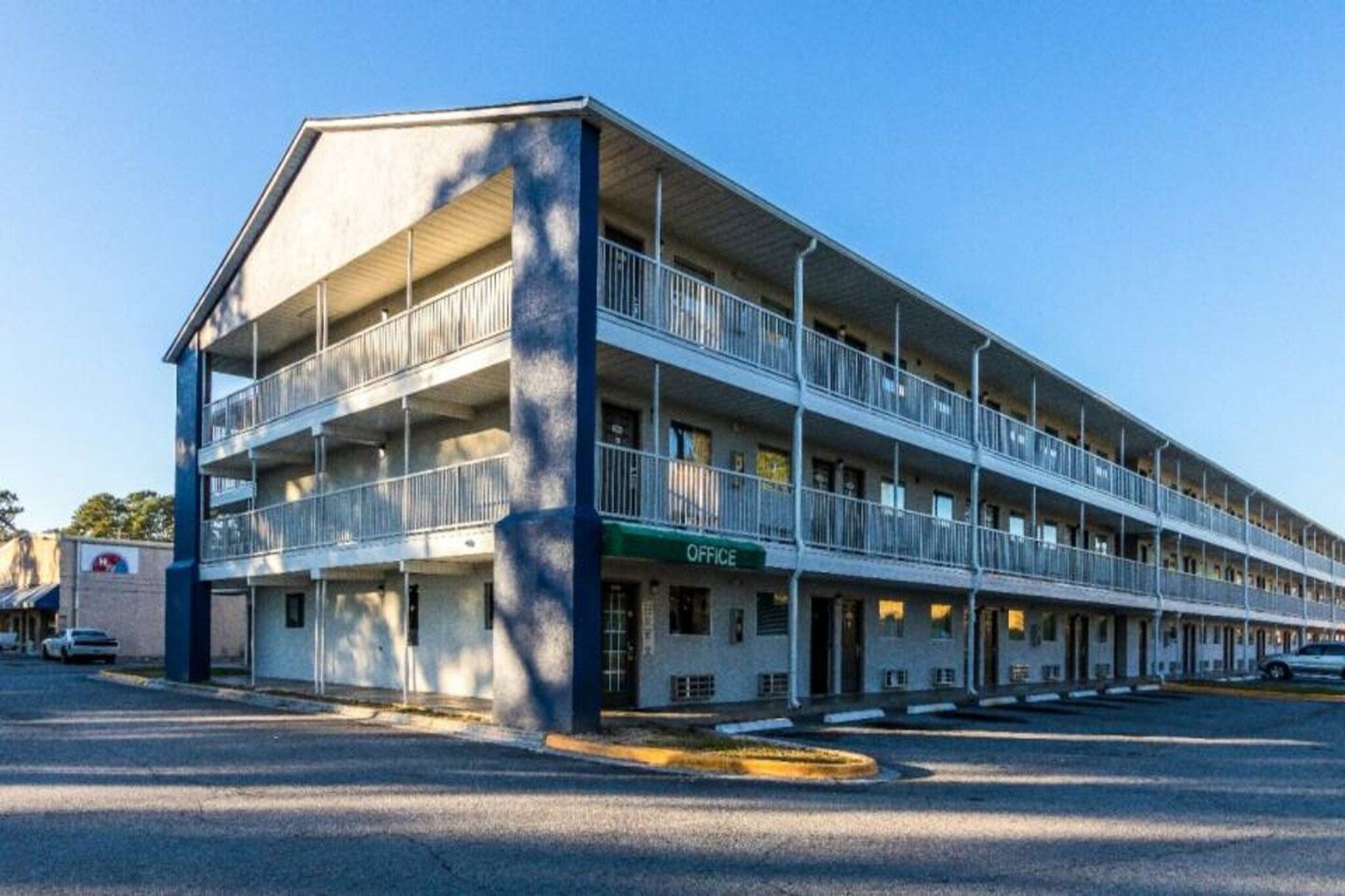A multi-story motel with a central office, multiple balconies, and a parking lot.