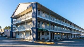 A multi-story motel with a central office, multiple balconies, and a parking lot.