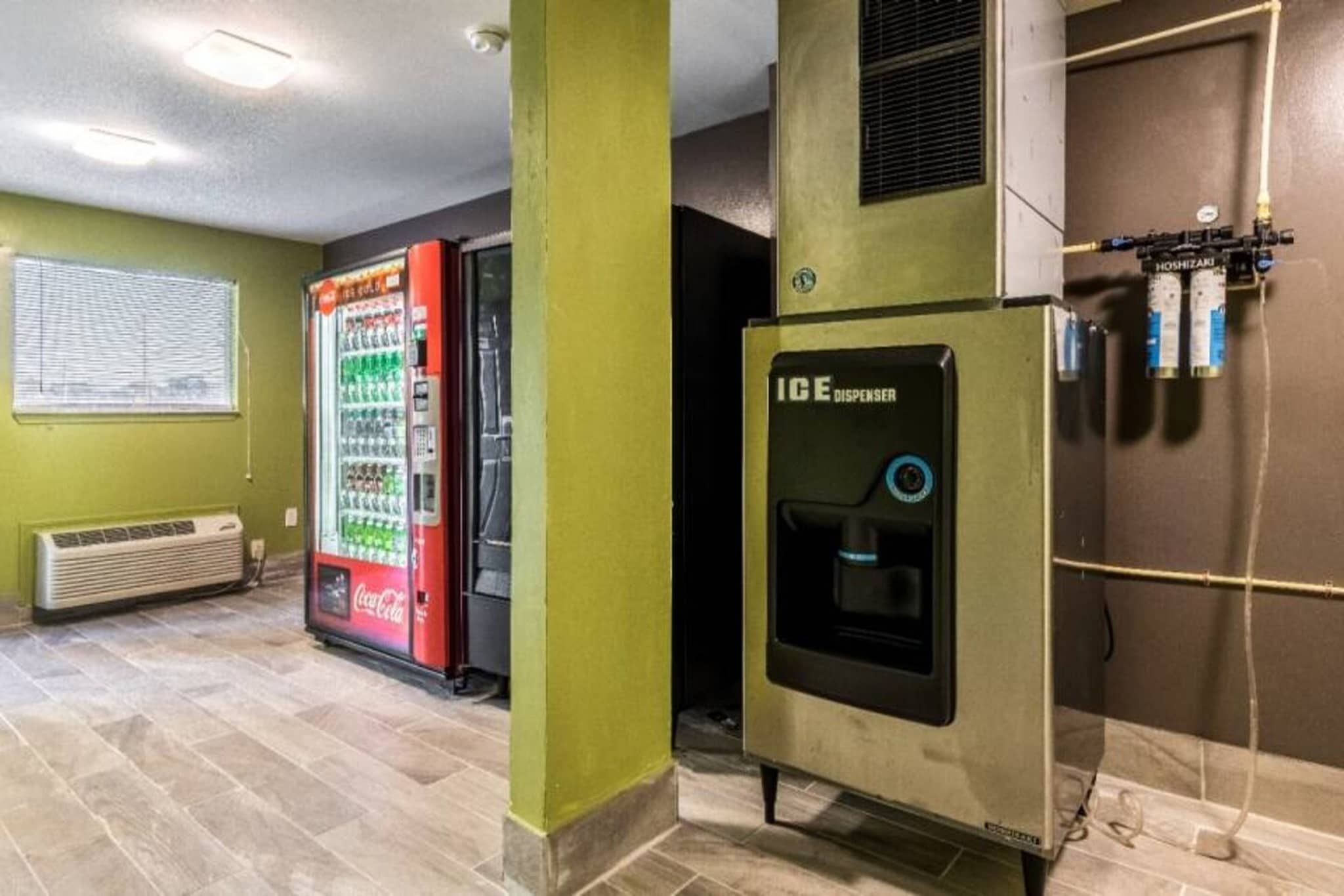 A room with a vending machine, a water dispenser, and a wall-mounted air conditioning unit.