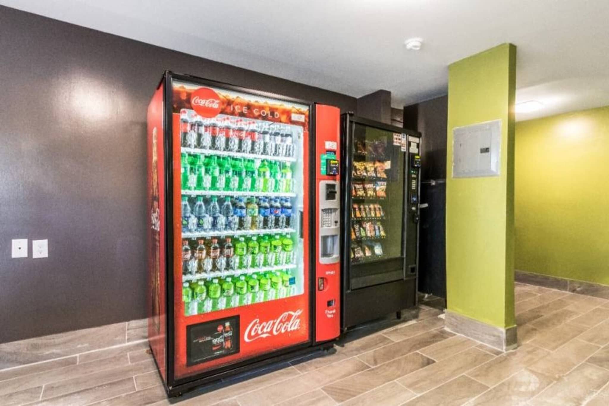 A vending machine area with a Coca-Cola branded machine stocked with beverages.
