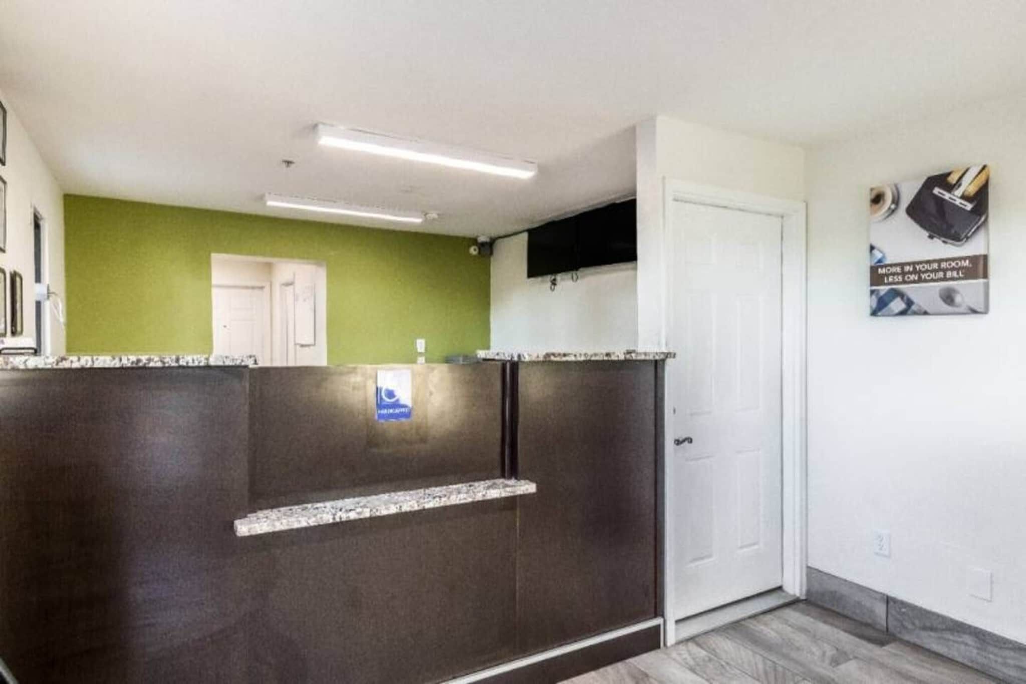 A reception area with a dark counter, a green wall, a white door, and a sign on the wall.