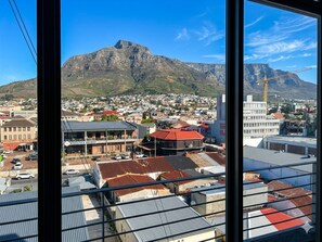 A cityscape with a prominent mountain in the background, a brewery building, and a crane. - Serene 1-bedroom Apartment in Central Cape Town (Cape Town)