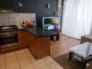 A modern kitchen with a built-in stove, oven, and a flat-screen TV on a stand. - Serene 1-bedroom Apartment in Central Cape Town (Cape Town)
