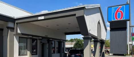 A motel with a covered parking area, a clear sky, and a sign indicating the motel number.