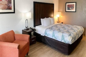 Ein Hotelzimmer mit einem Bett, zwei Nachttischen, einem Sessel und einem Beistelltisch.