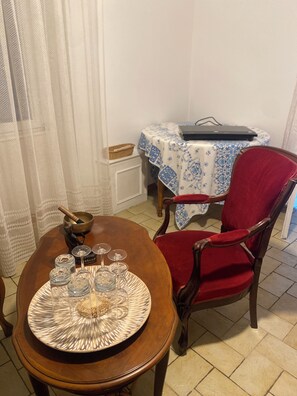 A dining area with a wooden table set for four, a red upholstered chair, and a small round table with a blue and white tablecloth. - Vrbo Property (Bains-sur-Oust)