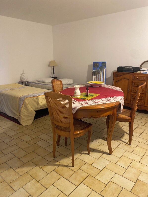 A small room with a bed, a table with chairs, a lamp, and a painting on the wall. - Vrbo Property (Bains-sur-Oust)
