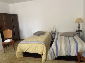 A room with two single beds, a chair, a small table with a lamp, and a wardrobe. - Vrbo Property (Bains-sur-Oust)