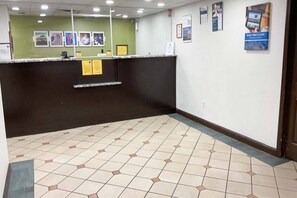 A reception area with a counter, a green wall with framed pictures, and a tiled floor. - 2 Full Beds  Non-Smoking Kitchen (Columbus GA)