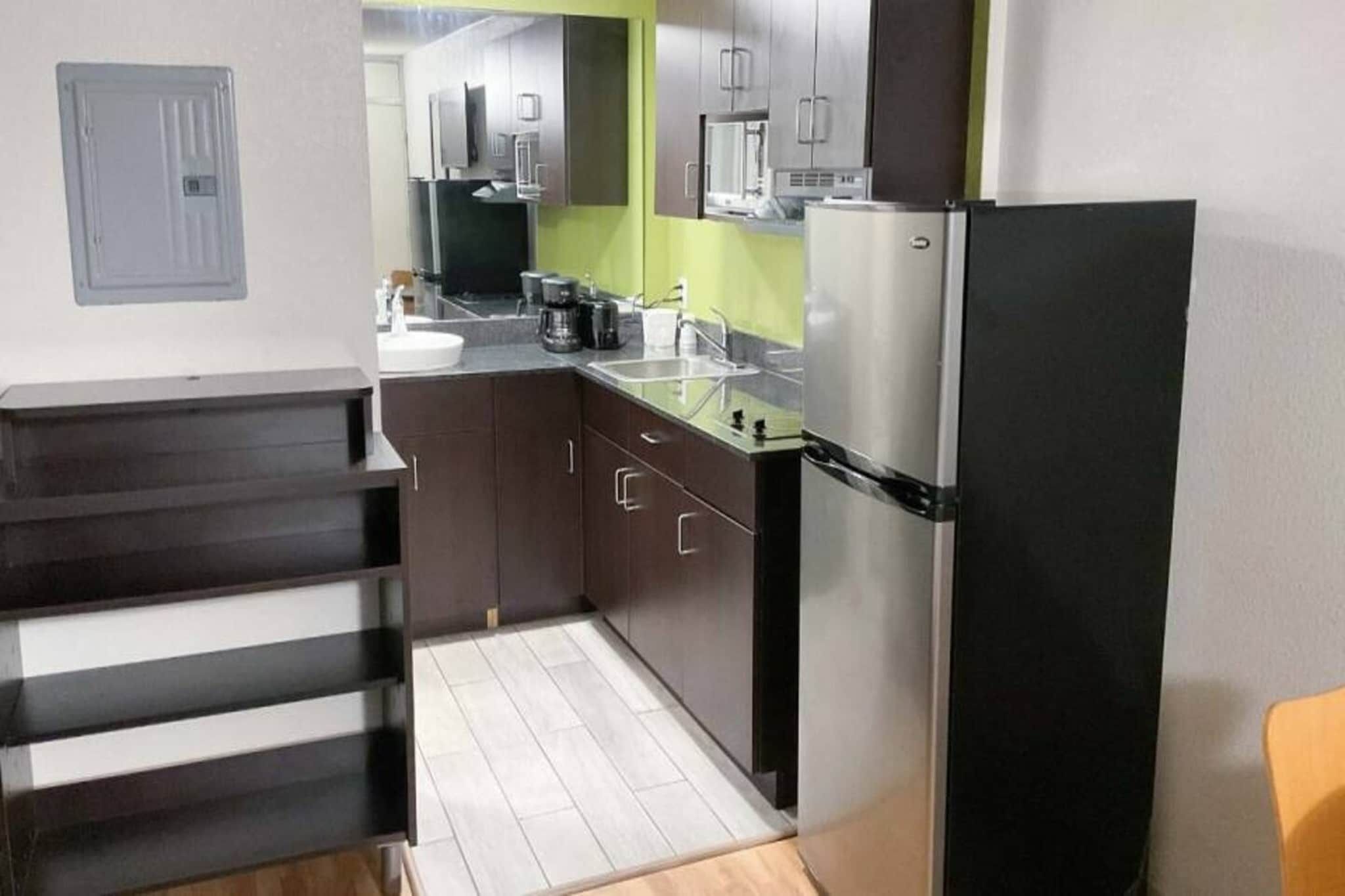 A compact kitchen with a refrigerator, sink, and a coffee maker.