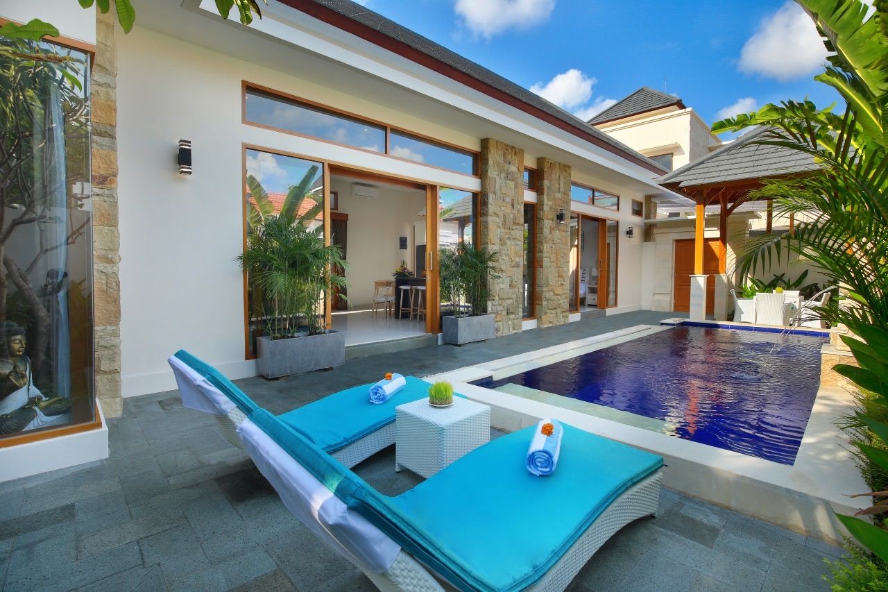 A modern house with a swimming pool, outdoor seating, and a large window.