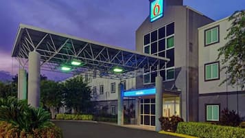 A hotel with a covered entrance, a prominent '6' logo, and a 'Welcome' sign.