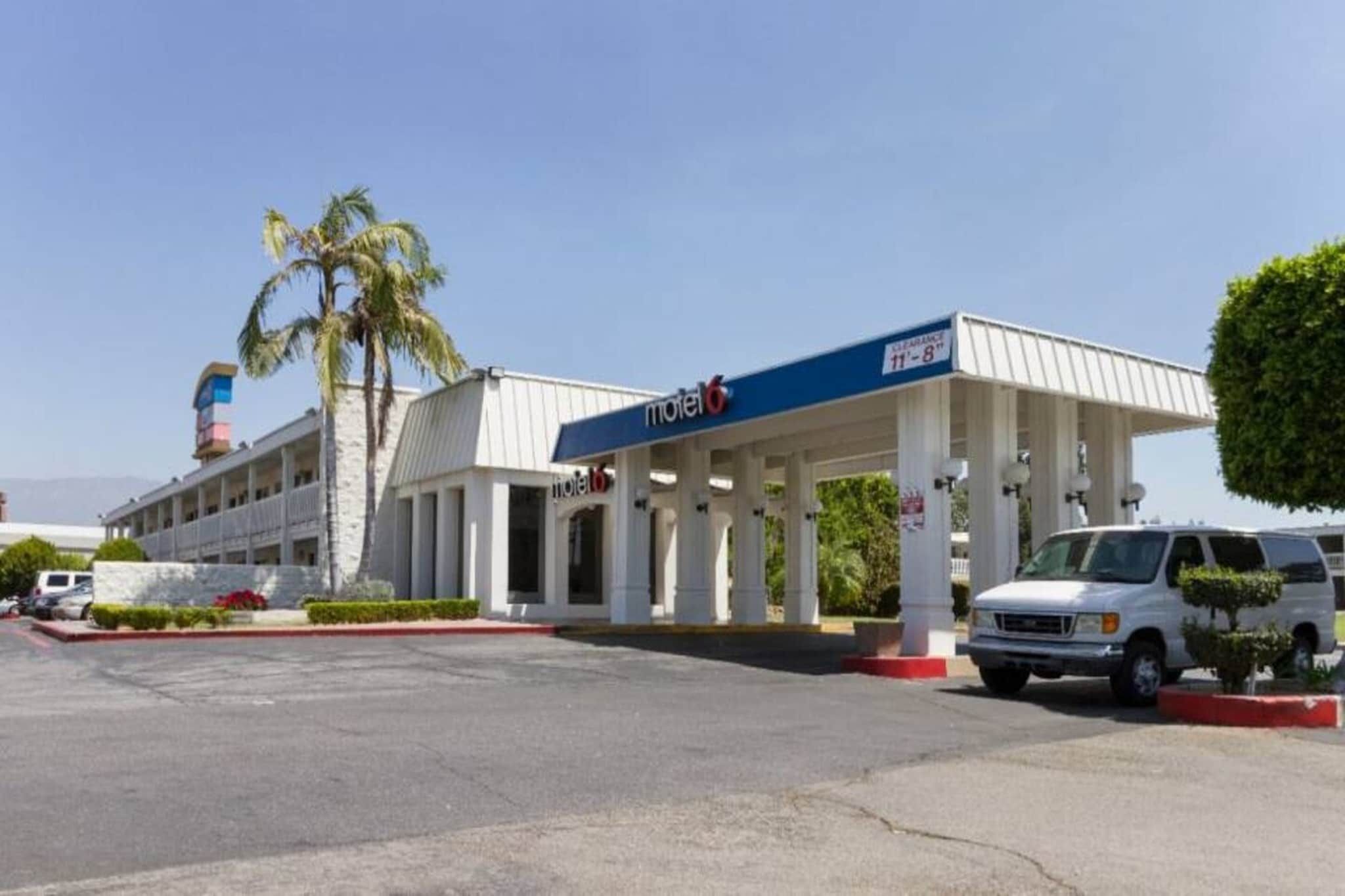A motel with a gas station, a parking lot, and a building with columns.
