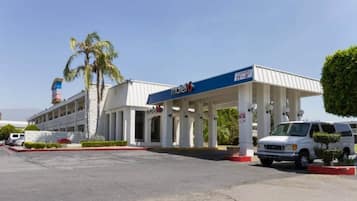 A motel with a gas station, a parking lot, and a building with columns.