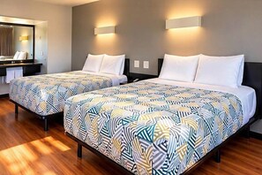 Une chambre d’hôtel avec deux lits, un bureau et un miroir.