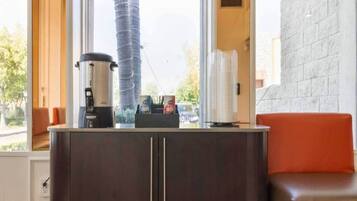 A kitchen area with a coffee maker, a cabinet with two doors, and a view of a tall building outside.