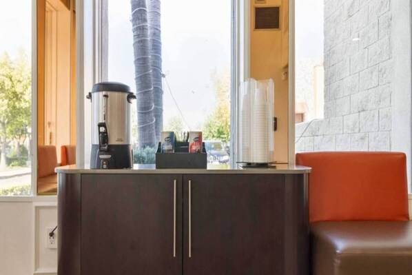 A kitchen area with a coffee maker, a cabinet with two doors, and a view of a tall building outside.