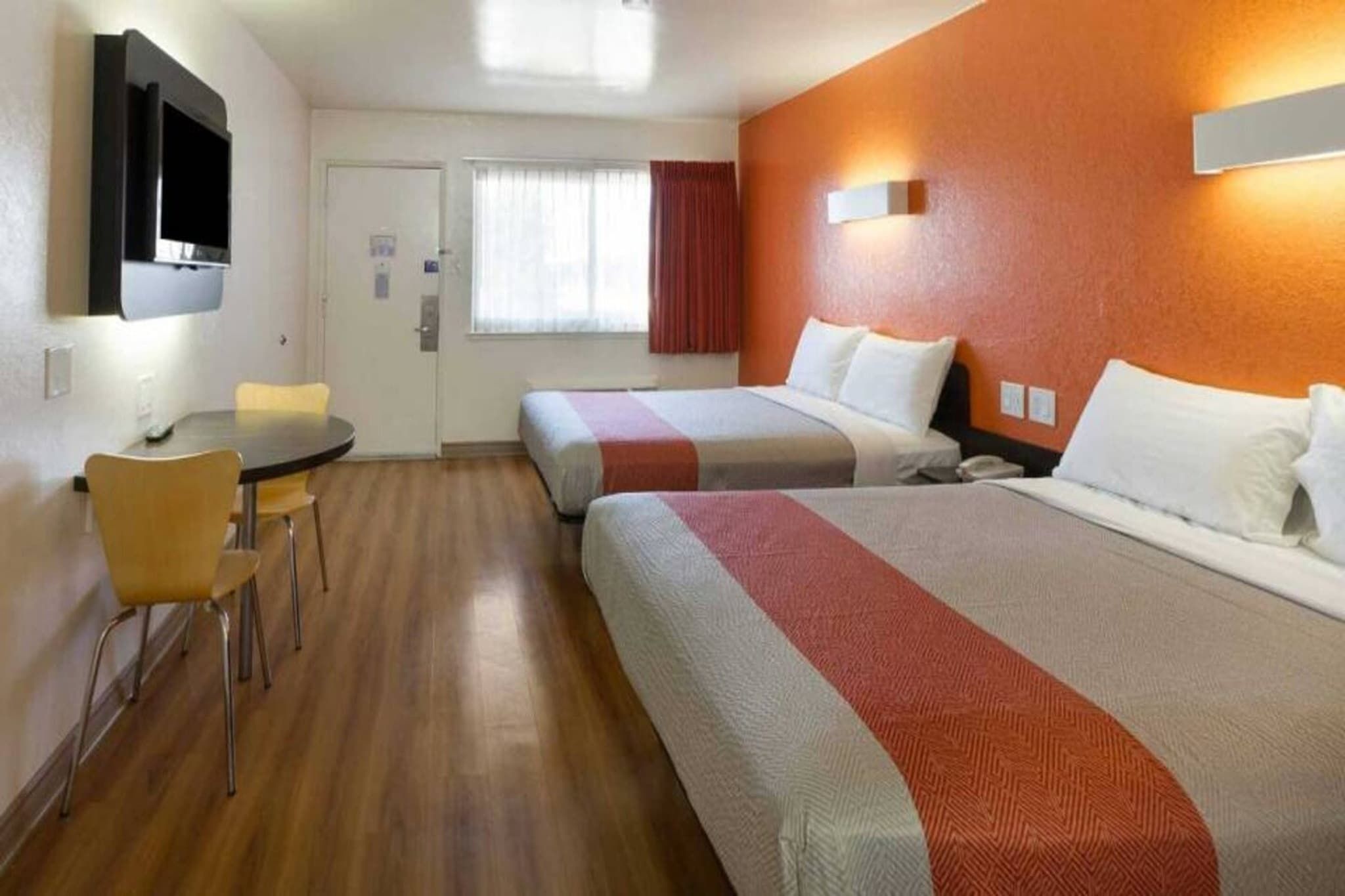 A hotel room with two beds, a desk, and a chair.