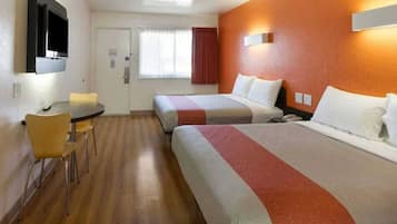 A hotel room with two beds, a desk, and a chair.