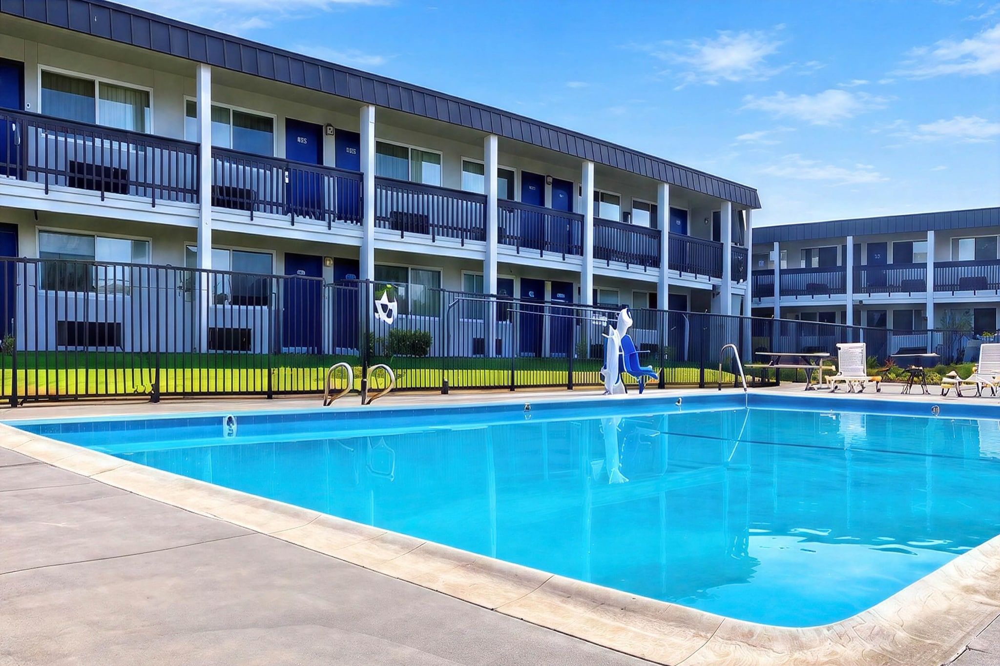 Hotel de diversos pisos amb piscina, balcons i zona tancada per una tanca.