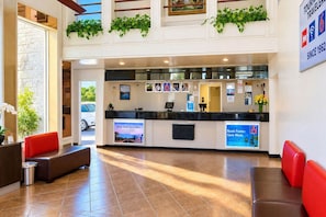 A hotel reception area with a counter, seating, and a view of the outside.