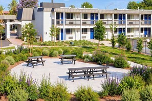 A multi-story hotel with outdoor seating areas and a landscaped garden.