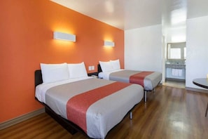 A hotel room with two beds, a wooden floor, and a kitchenette in the background. - 2 Queen Beds | Non-Smoking (Claremont)