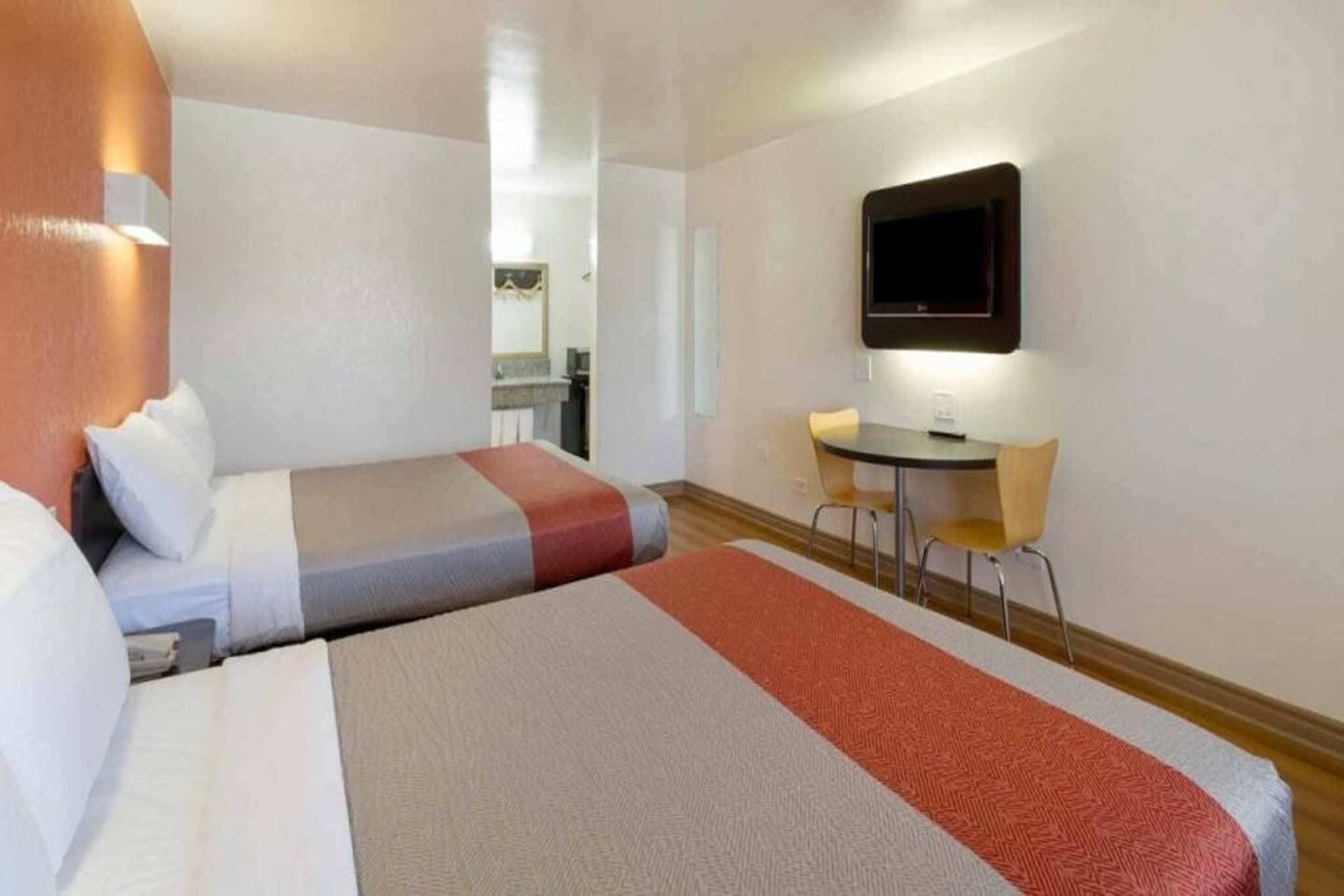 Een hotelkamer met twee bedden, een bureau en een televisie.