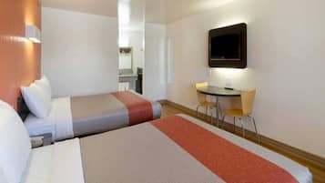 Een hotelkamer met twee bedden, een bureau en een televisie.