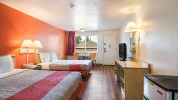 A hotel room with two beds, a desk, a television, and a window with a view.
