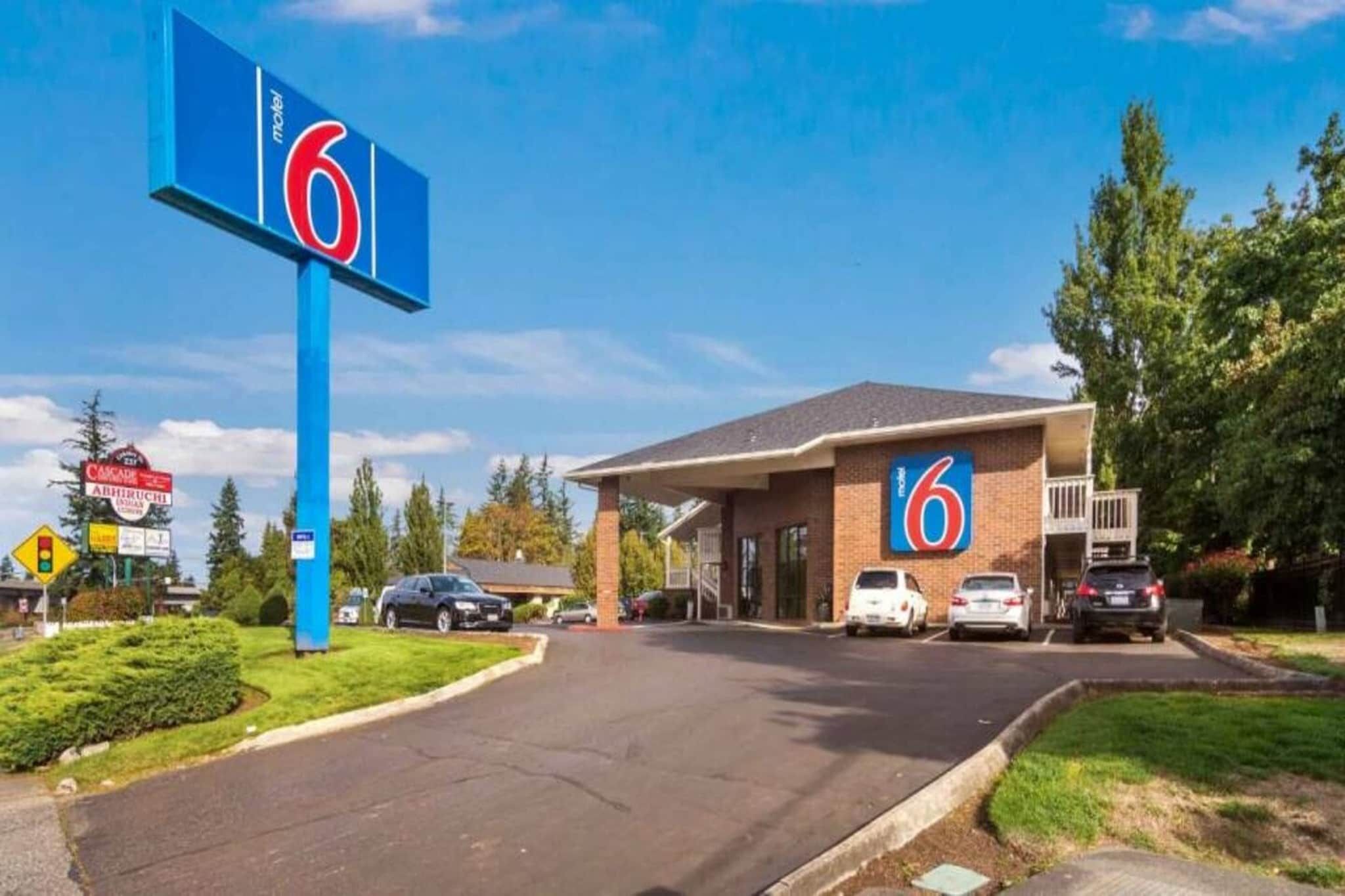 A motel with a prominent '6' sign, a parking lot, and a few cars parked in front.
