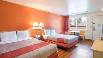 Quarto de hotel com duas camas, uma escrivaninha, uma cadeira e uma janela.