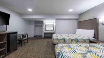 A hotel room with a bed, a desk, a chair, a television, and a wardrobe.