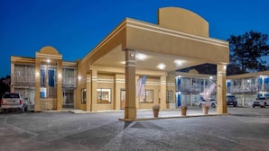 A hotel entrance with a covered waiting area, a flag, and a parking lot. - 3 Queen Beds | Non-Smoking, Kitchen (Effingham)