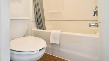 Un baño con inodoro, bañera y cortina de ducha.