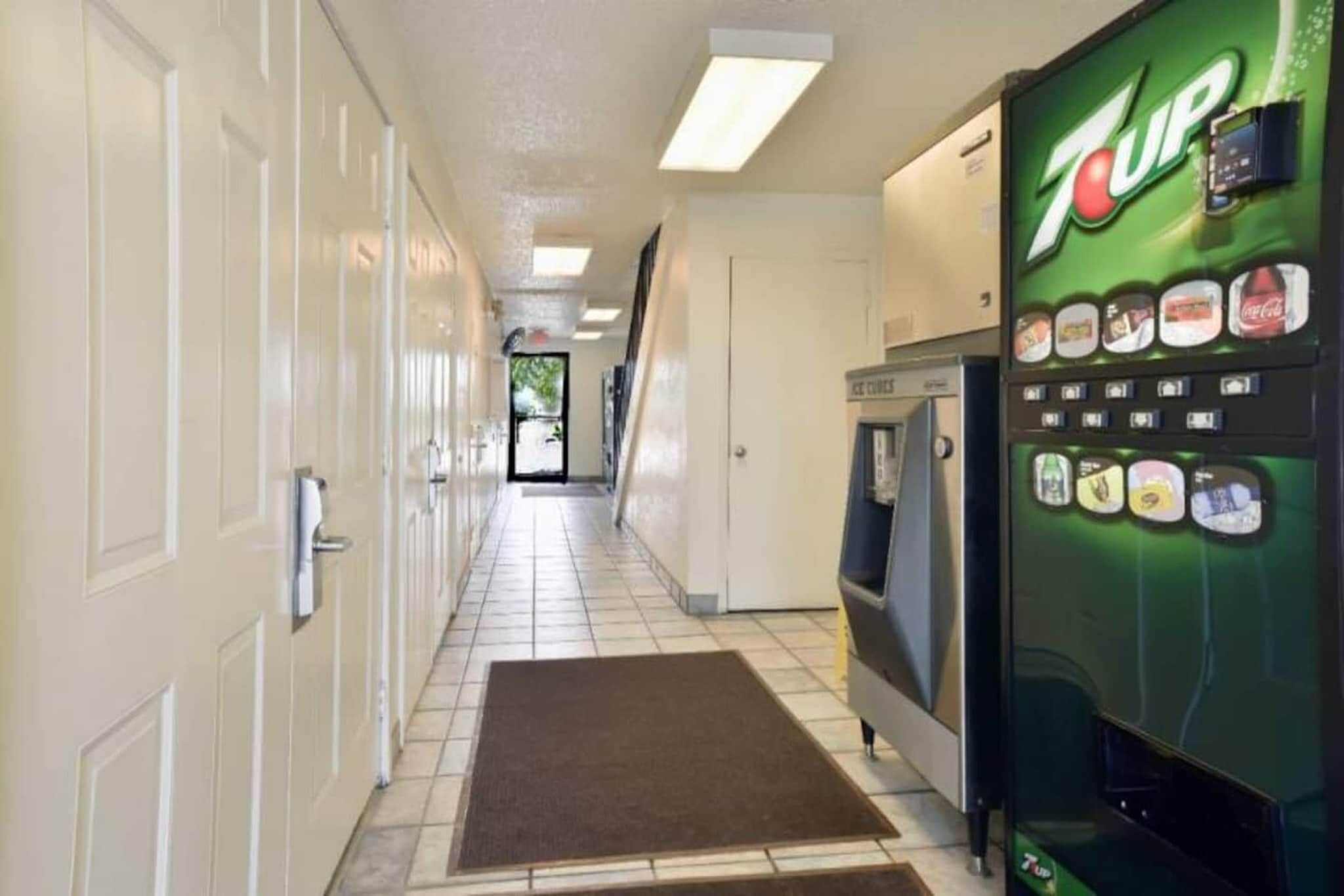 A hallway with a 7UP vending machine, a microwave, and a door leading to another room.