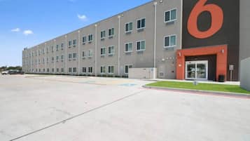 A modern building with a large '6' sign, multiple windows, and a parking lot.